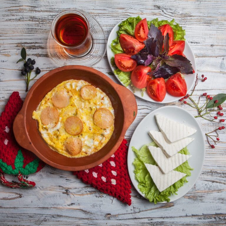 top view fried eggs with sausages with chopped tomatoes cheese glass tea clay plate scaled 1