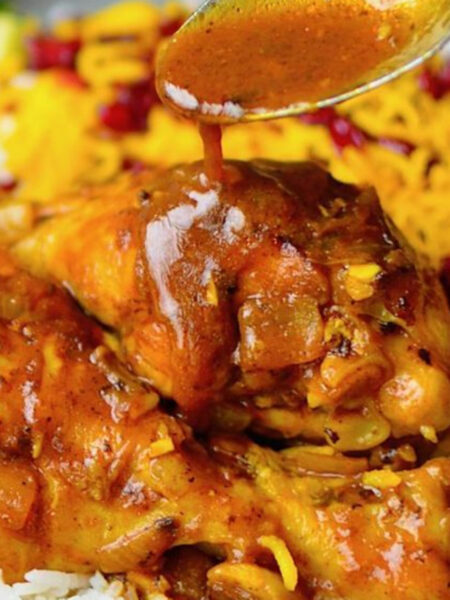 Golden saffron chicken served with pistachios and herbs in a rustic bowl.