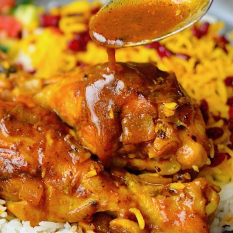 Golden saffron chicken served with pistachios and herbs in a rustic bowl.